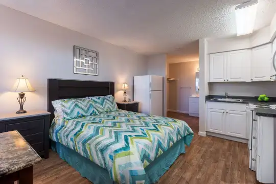 bedroom with hardwood flooring, refrigerator, and range oven