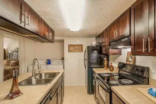 kitchen with extractor fan, dishwasher, electric range oven, washer / dryer, refrigerator, dark brown cabinetry, light granite-like countertops, and light tile floors