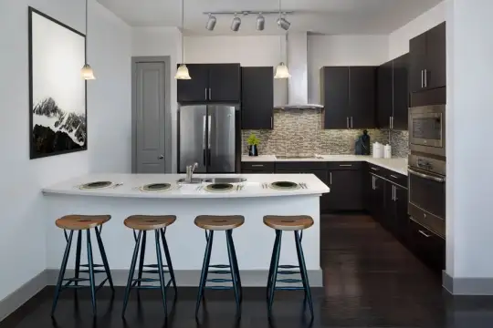 kitchen featuring a breakfast bar, stainless steel appliances, ventilation hood, dark parquet floors, pendant lighting, dark brown cabinetry, and light countertops