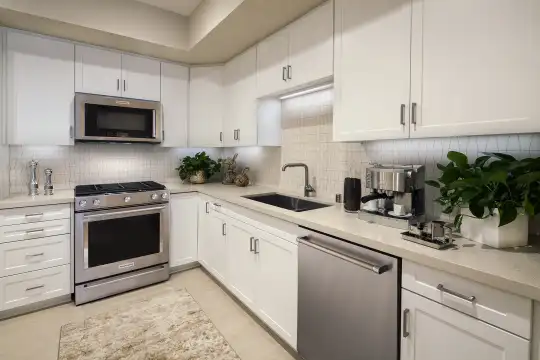 kitchen with gas range oven, stainless steel appliances, light countertops, white cabinetry, and light hardwood flooring