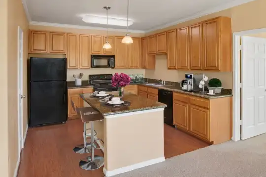 kitchen with a kitchen island, range oven, refrigerator, dishwasher, microwave, pendant lighting, brown cabinets, and light hardwood floors