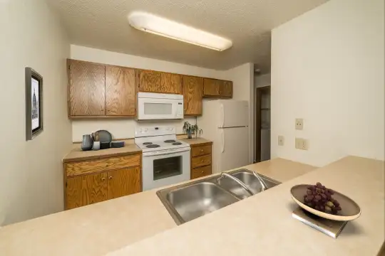 kitchen with refrigerator, electric range oven, microwave, brown cabinets, and light countertops