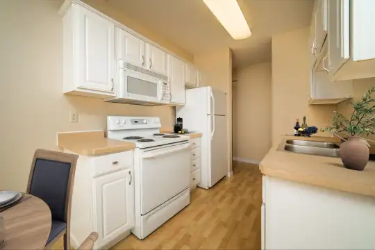 kitchen with refrigerator, electric range oven, microwave, light hardwood floors, white cabinets, and light countertops