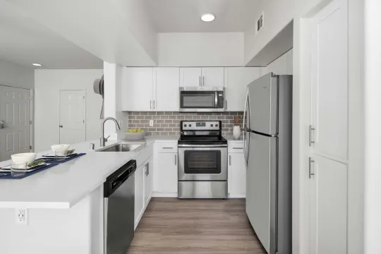 kitchen featuring stainless steel appliances, electric range oven, light countertops, white cabinets, and light hardwood floors