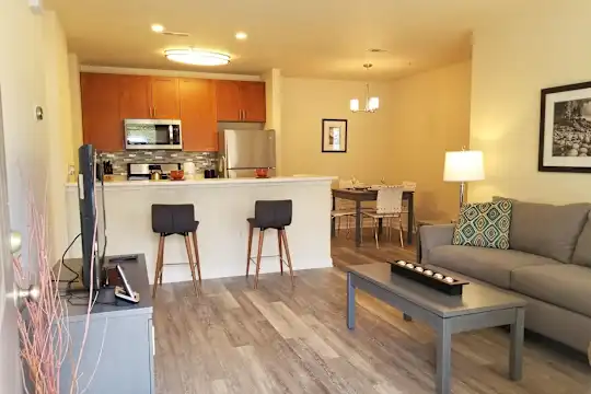 hardwood floored living room featuring a kitchen bar, stainless steel refrigerator, TV, and microwave