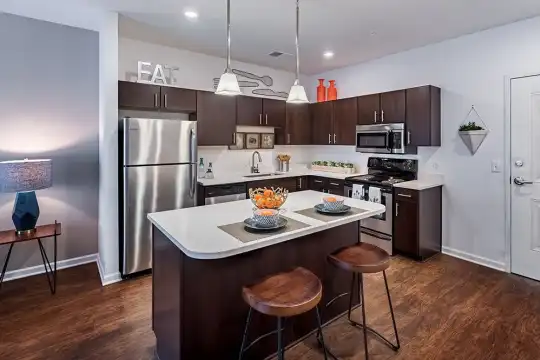 kitchen featuring a breakfast bar area, electric range oven, stainless steel appliances, dark brown cabinets, dark parquet floors, light countertops, and pendant lighting