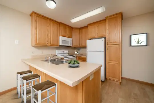 kitchen featuring a breakfast bar, refrigerator, electric range oven, microwave, light countertops, brown cabinetry, and light parquet floors