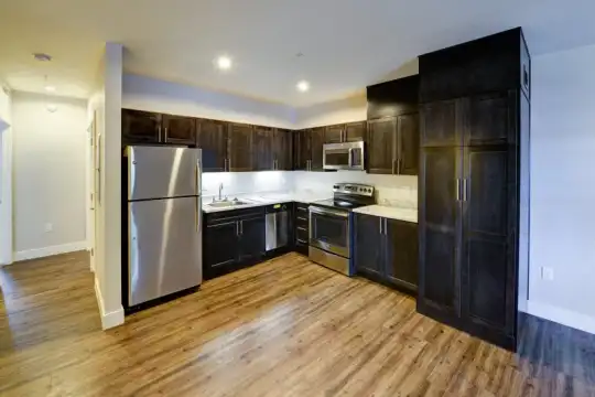kitchen featuring stainless steel refrigerator, dishwasher, electric range oven, microwave, light hardwood flooring, dark brown cabinets, and light countertops