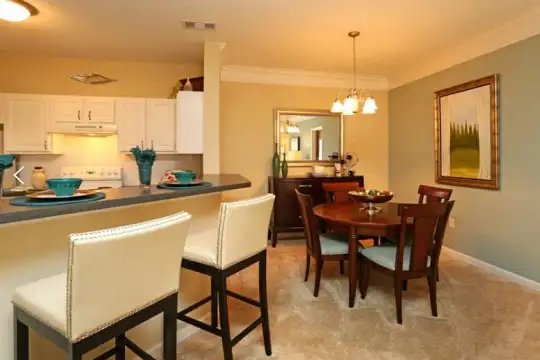 kitchen with a breakfast bar, carpet, extractor fan, range oven, light flooring, dark countertops, and white cabinets