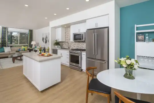 kitchen with a center island, natural light, stainless steel appliances, gas range oven, white cabinetry, light parquet floors, and light countertops