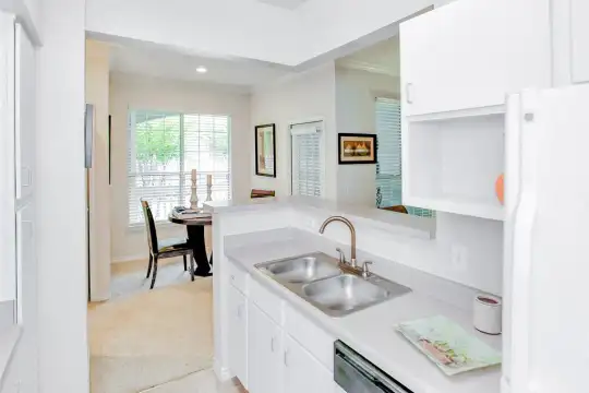 kitchen with carpet, natural light, refrigerator, dishwasher, light flooring, white cabinets, and light countertops