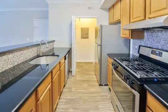 kitchen with ventilation hood, gas range oven, dishwasher, light hardwood floors, and brown cabinets