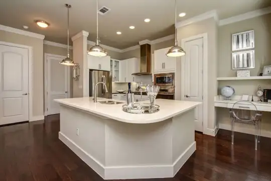 kitchen featuring ventilation hood, oven, stainless steel refrigerator, microwave, white cabinets, light countertops, dark parquet floors, a kitchen island with sink, and pendant lighting