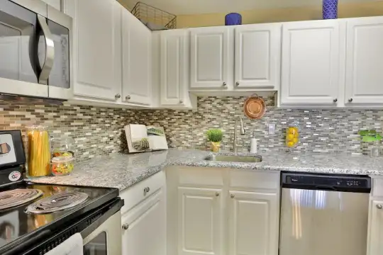 kitchen with stainless steel appliances, white cabinetry, and granite-like countertops