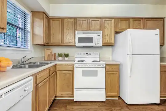 kitchen featuring natural light, refrigerator, electric range oven, dishwasher, microwave, light parquet floors, light countertops, and brown cabinetry