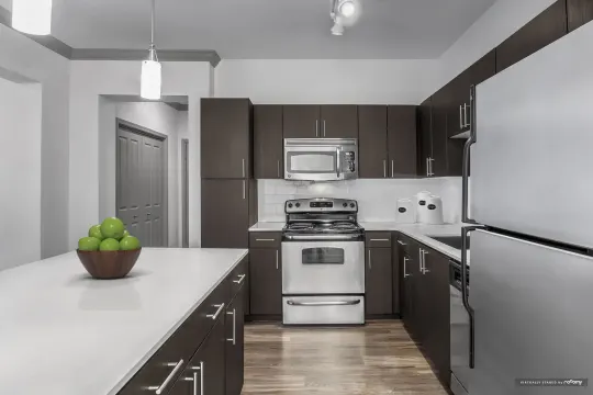 kitchen featuring a kitchen island, refrigerator, dishwasher, electric range oven, stainless steel microwave, pendant lighting, light parquet floors, and dark brown cabinetry