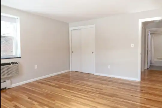 hardwood floored empty room featuring natural light and baseboard radiator