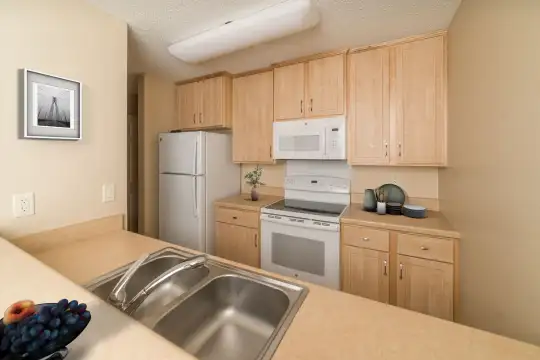 kitchen featuring refrigerator, electric range oven, microwave, light brown cabinetry, and light countertops