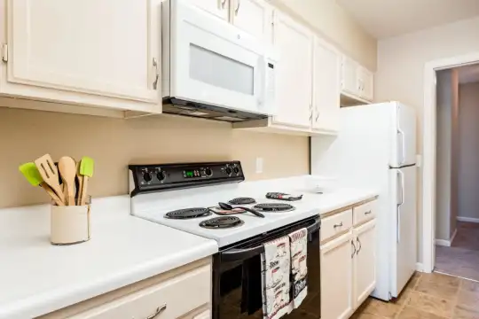 kitchen featuring refrigerator, electric range oven, microwave, light tile floors, white cabinetry, and light countertops
