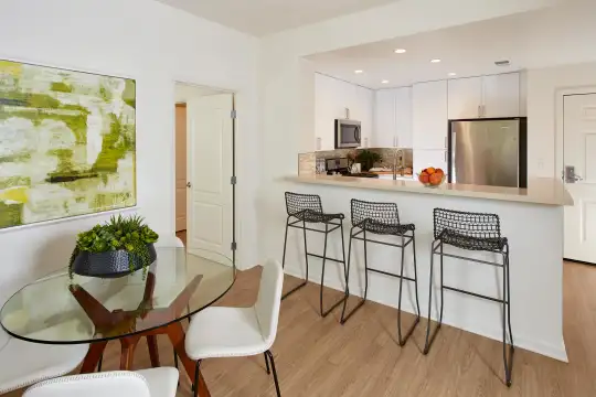 kitchen featuring a breakfast bar area, stainless steel refrigerator, microwave, range oven, light hardwood floors, white cabinets, and light countertops