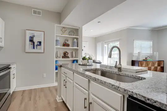 kitchen with a healthy amount of sunlight, stainless steel microwave, electric range oven, dishwasher, white cabinetry, light stone countertops, and light hardwood flooring