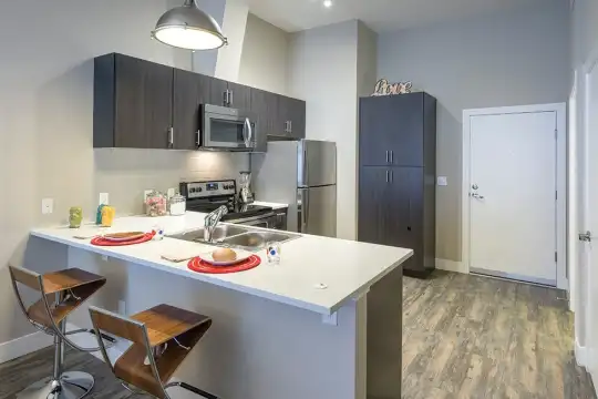 kitchen featuring a breakfast bar, stainless steel appliances, range oven, dark brown cabinetry, light countertops, and dark hardwood flooring