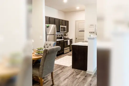 kitchen featuring stainless steel microwave, refrigerator, electric range oven, dark brown cabinets, light countertops, and light hardwood floors