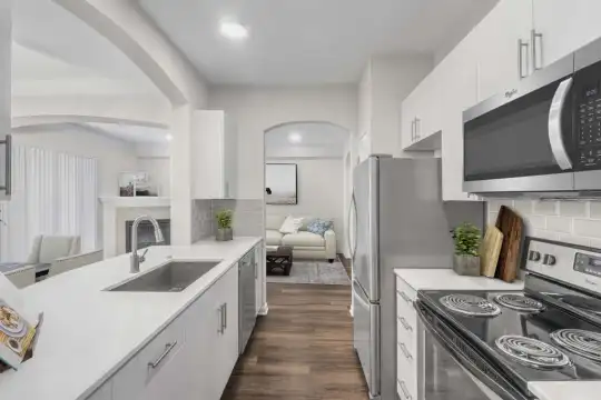 kitchen featuring stainless steel microwave, electric range oven, dishwasher, light countertops, white cabinetry, and dark hardwood floors