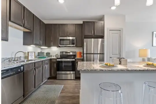 kitchen featuring stainless steel appliances, range oven, granite-like countertops, dark brown cabinetry, and dark floors