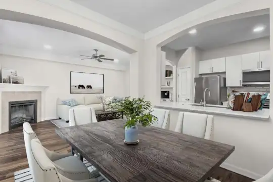 dining space with a ceiling fan, hardwood floors, a fireplace, stainless steel refrigerator, and microwave