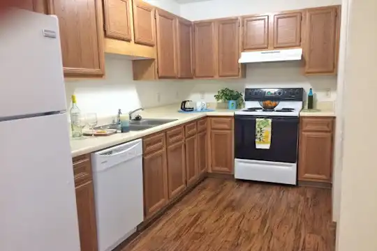 kitchen featuring ventilation hood, refrigerator, electric range oven, dishwasher, light countertops, dark hardwood floors, and brown cabinetry