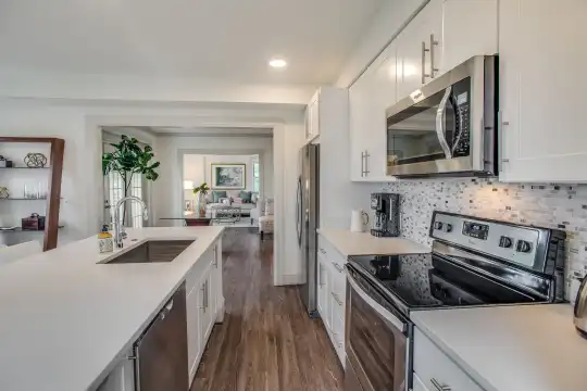 kitchen featuring a kitchen island, electric range oven, stainless steel appliances, white cabinets, light countertops, and dark hardwood flooring