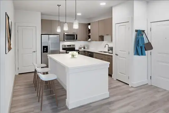 kitchen with a center island, stainless steel appliances, range oven, light brown cabinetry, light hardwood floors, light countertops, and pendant lighting