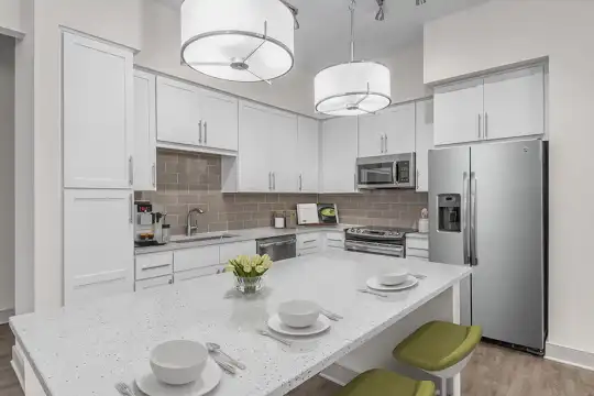 kitchen featuring stainless steel appliances, range oven, white cabinetry, light hardwood flooring, pendant lighting, and light stone countertops