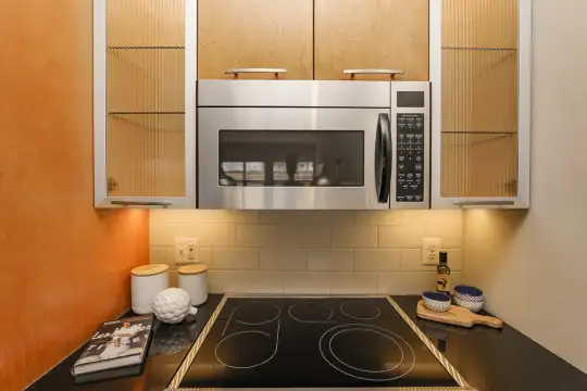 kitchen with electric stovetop, microwave, light countertops, and brown cabinetry