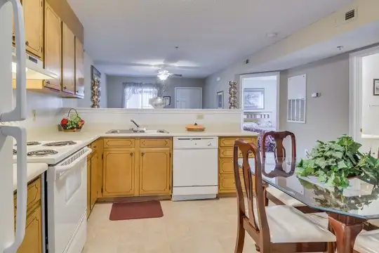 kitchen with electric range oven, refrigerator, dishwasher, fume extractor, light tile floors, brown cabinets, and light countertops