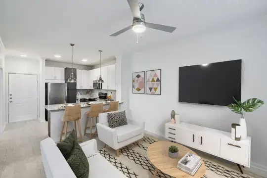 living room featuring a ceiling fan, a breakfast bar area, stainless steel refrigerator, range oven, TV, and microwave