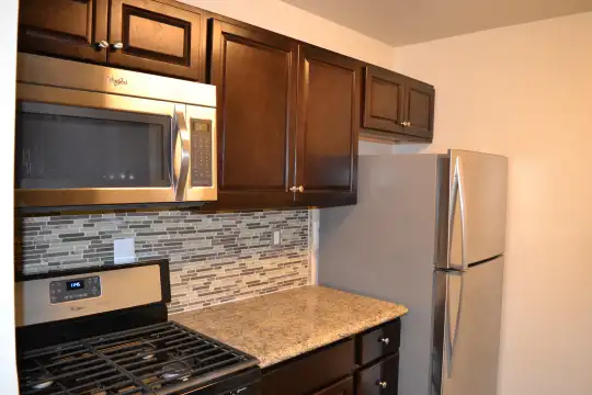 kitchen featuring stainless steel appliances, dark brown cabinets, and dark stone countertops