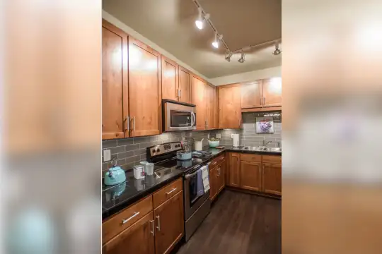 kitchen featuring electric range oven, stainless steel microwave, dark countertops, dark parquet floors, and brown cabinets