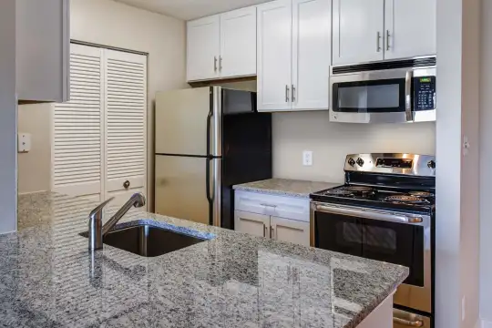kitchen featuring a kitchen island, stainless steel microwave, refrigerator, electric range oven, granite-like countertops, light floors, and white cabinets