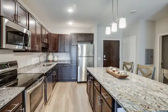 kitchen featuring stainless steel appliances, electric range oven, pendant lighting, light stone countertops, dark brown cabinetry, and light parquet floors