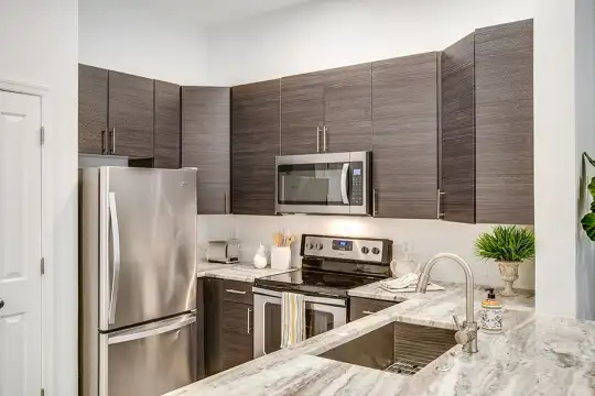 kitchen featuring electric range oven, stainless steel appliances, light granite-like countertops, and dark brown cabinets
