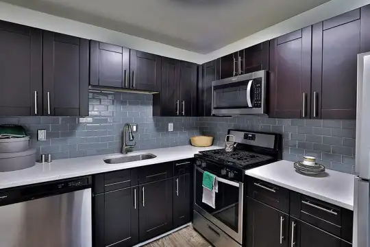 kitchen with stainless steel appliances, gas range oven, light flooring, dark brown cabinetry, and light countertops