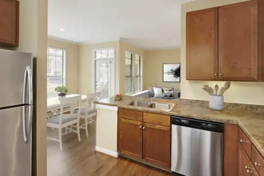 kitchen featuring a wealth of natural light, stainless steel appliances, granite-like countertops, light hardwood flooring, and brown cabinetry