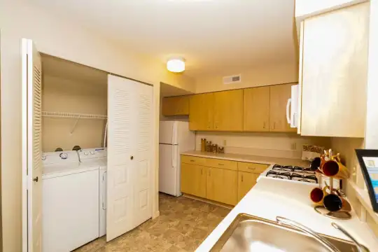 kitchen featuring refrigerator, separate washer and dryer, microwave, light countertops, light tile floors, and brown cabinets