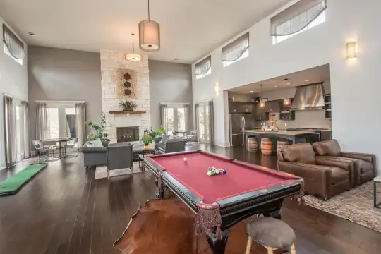 recreation room with a wealth of natural light, a high ceiling, hardwood flooring, a fireplace, refrigerator, and exhaust hood