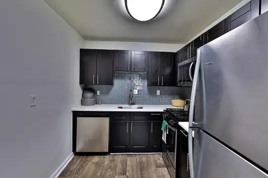 kitchen with stainless steel appliances, range oven, dark parquet floors, light countertops, and dark brown cabinets