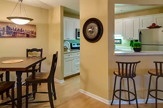 kitchen with a kitchen breakfast bar, refrigerator, range oven, white cabinetry, light hardwood floors, pendant lighting, and light countertops