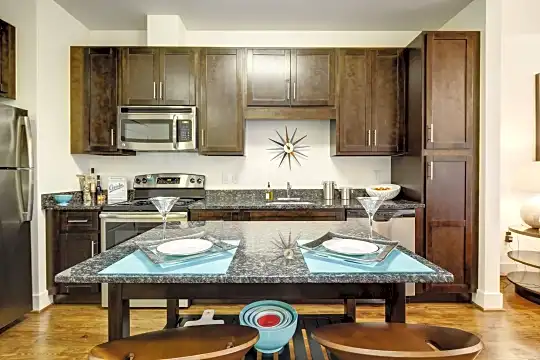 kitchen with electric range oven, stainless steel appliances, light floors, dark brown cabinetry, and stone countertops