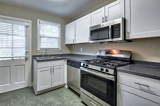 kitchen with a healthy amount of sunlight, stainless steel microwave, gas range oven, dishwasher, dark tile floors, dark countertops, and white cabinets